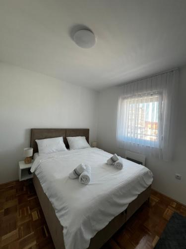 a bedroom with a large white bed with towels on it at City Nest, Free Parking & City Center in Prijedor