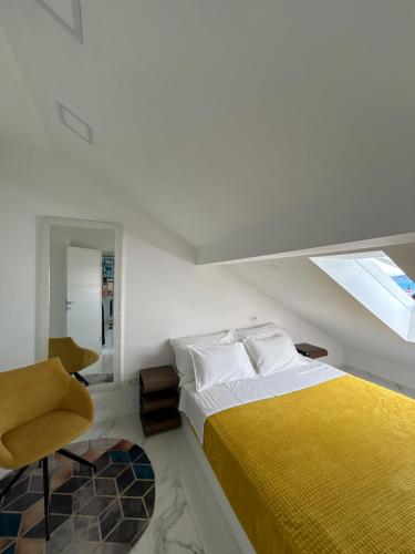 a white bedroom with a yellow bed and a chair at New apartman Summer in Kaštela