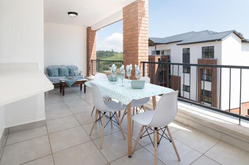 a dining room with a table and chairs on a balcony at Ballito Hills 478 in Ballito