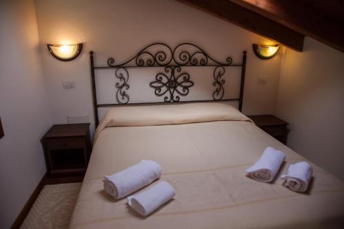 a bedroom with a white bed with towels on it at Su Ghindalu Guesthouse in Villanova Monteleone