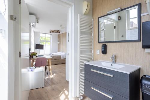 a bathroom with a sink and a bedroom with a bed at Stadslogement Kingsize in Sneek