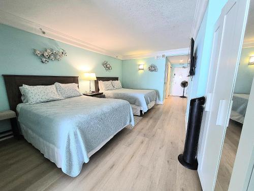 a hotel room with two beds and a flat screen tv at Sunkissed-Modern Oceanfront Condo Daytona Beach in Daytona Beach
