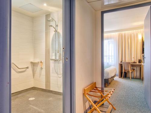 a bathroom with a shower and a bedroom at Mercure Trouville Sur Mer in Trouville-sur-Mer