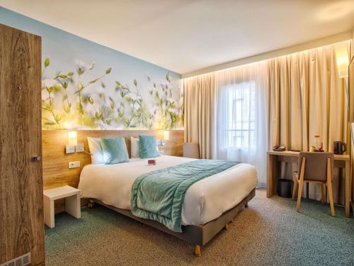 a hotel room with a bed and a painting of flowers at Mercure Trouville Sur Mer in Trouville-sur-Mer