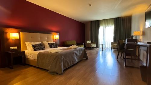 a bedroom with a large bed with a red wall at Palace Hotel & Spa Termas de São Tiago in Penamacor