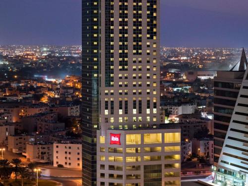 a tall building with a red sign on the side of it at ibis Seef Manama in Manama