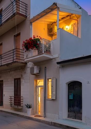 a building with a balcony with flowers on it at Libeccio House in Avola