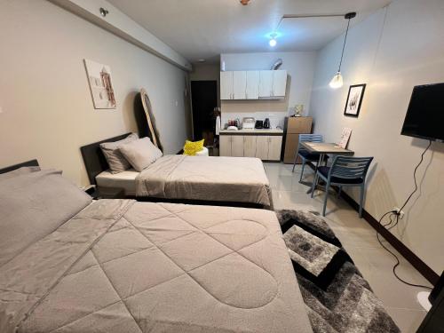 a bedroom with two beds and a table and a kitchen at JIYA Studio and Breakfast in Cebu City