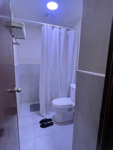 a bathroom with a toilet and a white shower curtain at JIYA Studio and Breakfast in Cebu City