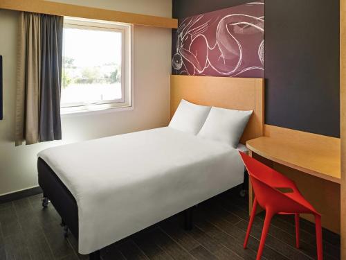 a bedroom with a bed and a desk and a red chair at Ibis Culiacan in Culiacán