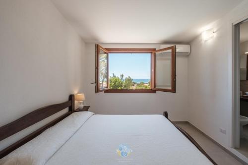 a white bedroom with a bed and a window at Villa Panorama Private Pool Costa Rei in Monte Nai