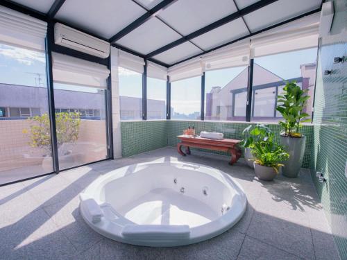 a large bath tub in a room with windows at Mercure Curitiba Batel in Curitiba