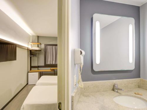 a bathroom with two beds and a sink and a phone at ibis Rio de Janeiro Nova America in Rio de Janeiro