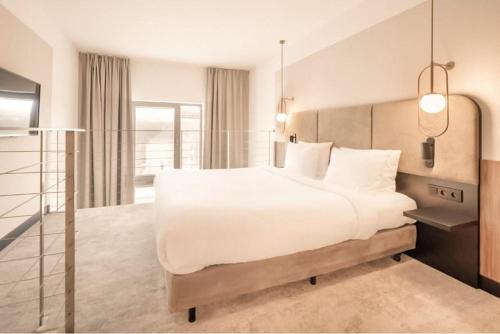 a bedroom with a large white bed and a window at Royal VIP in Kołobrzeg
