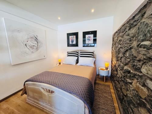 a bedroom with a bed and a stone wall at Estúdio Villa Matilde e Joaquim in Porto da Cruz