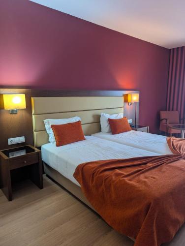 a hotel room with a large bed with orange pillows at Palace Hotel Astúrias & Spa in Carvalhal