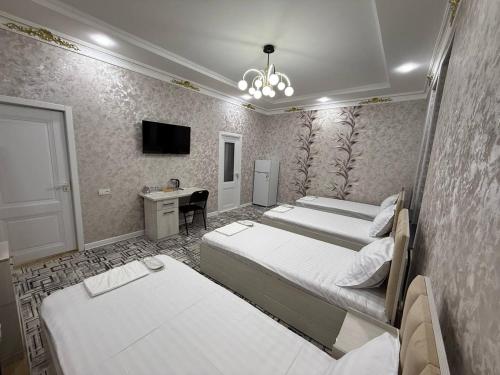 a bedroom with two beds and a desk and a television at Golden Emir Residence in Bukhara