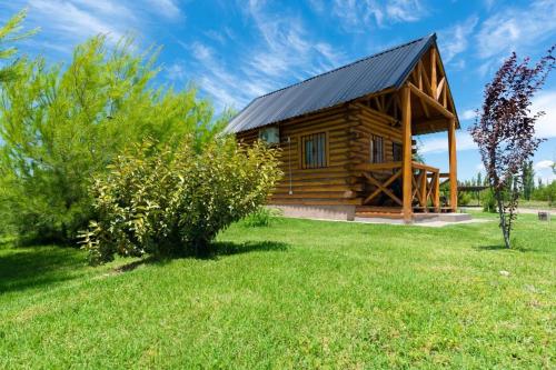 a log cabin with a black roof on a grass field at Finca La Vilina - Tiny House in San Rafael