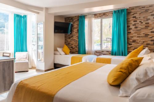 two beds in a hotel room with blue curtains at Xperience Hotel in Baños