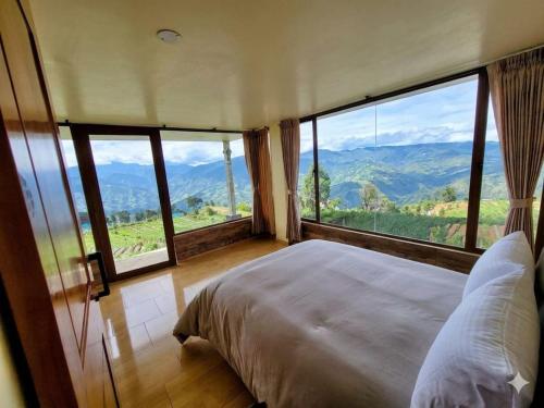 a bedroom with a large bed and large windows at Inti Amanta Lodge in Sigchos