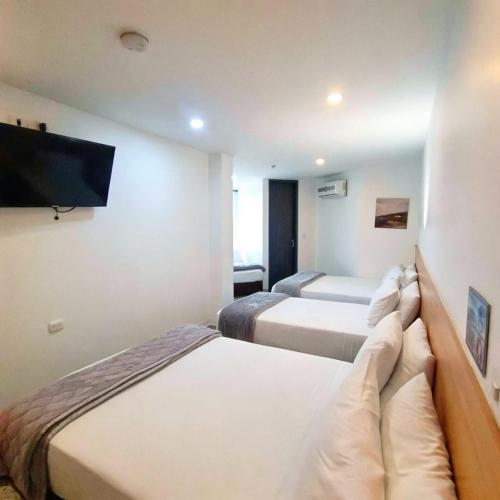 a hotel room with two beds and a flat screen tv at Bianco Hotel Boutique in Cúcuta