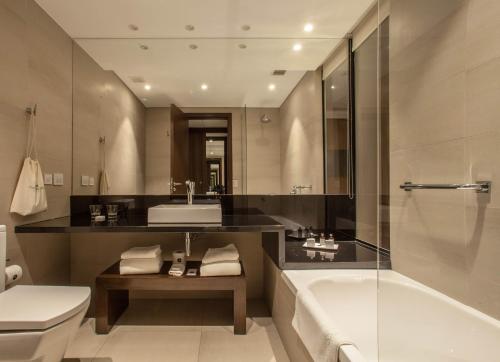 a bathroom with a tub and a toilet and a sink at Puerto Norte Design Hotel in Rosario