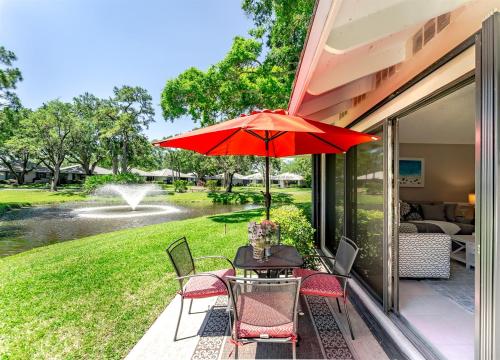 a table with a red umbrella on a patio at Upscale 2BR Townhome Golf, Pools & Lake Views in Palm Beach Gardens