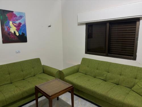 a living room with two green couches and a table at Ahmmad Alshgoor in Şirfah