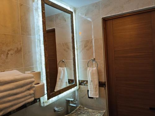 a bathroom with a mirror and a sink with towels at umbral luxury apartment in Tlajomulco