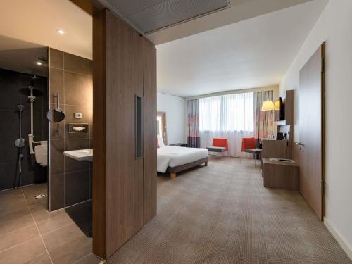 a hotel room with a bed and a bathroom at Novotel München City Arnulfpark in Munich
