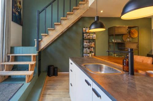 a kitchen with a sink and a staircase at Thús yn Hantum Vakantiehuisje met hottub in Friesland in Hantum