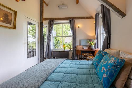 a bedroom with a large blue bed and a window at The Stables in Kampen