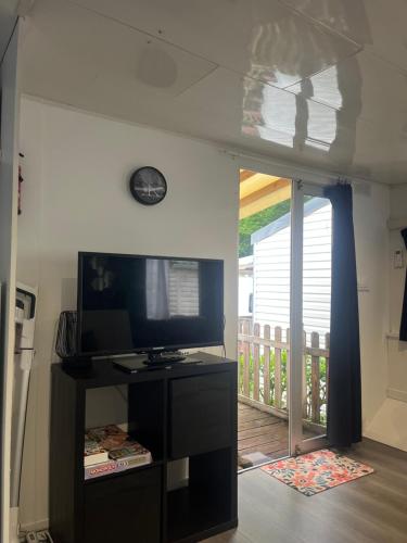 a living room with a television and a balcony at Mobil-home dans un camping calme et familial chez César in Cambo-les-Bains