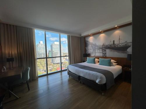 a bedroom with a large bed and a large window at Puerto Norte Design Hotel in Rosario