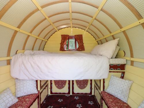 a bed in a tiny house with two chairs at The Bowtop Gypsy Caravan in Eye