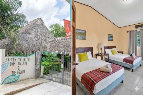 two beds in a room with a balcony at Drift Inn Cayo in Santa Elena