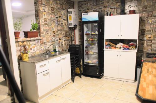 a kitchen with white cabinets and a refrigerator at Backpackers House - Near The Airport in Santiago
