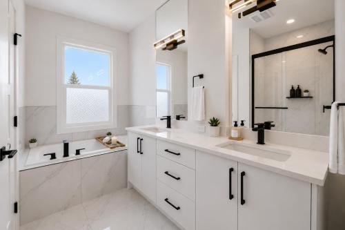 a white bathroom with two sinks and a shower at Emerald - 10mins from Stampede Park in Calgary