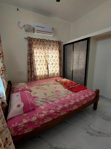 a bedroom with a large bed with a pink blanket at AGM Spacious Private AC 1BHK with Hall, Kitchen & Bath in Udupi