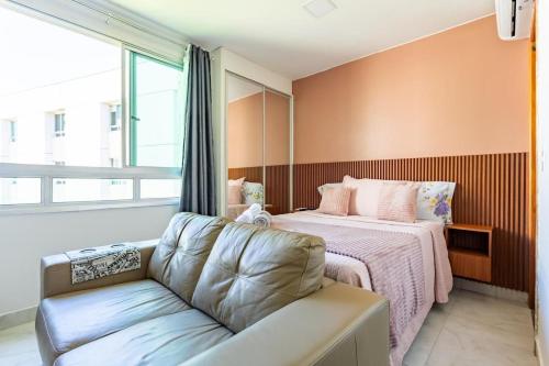a bedroom with a bed with a couch and a window at Flat Sudoeste Vienna by CentoEdez in Brasília