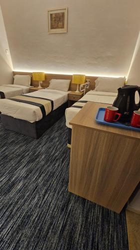 a hotel room with three beds and a table with a tray at فندق سكب الأصيل in An Naqāʼ