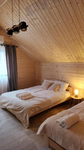 two beds in a room with a wooden ceiling at Lipowe Love in Lipowa
