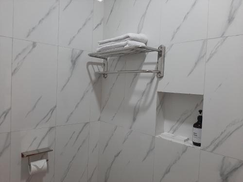 a bathroom with white marble walls and a towel rack at Gayo Belangi Resort in Tretet