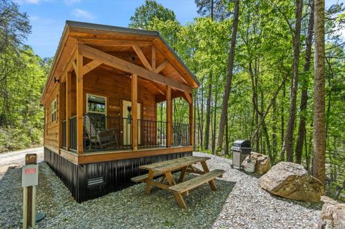 a small wooden cabin in the woods with a picnic table at Nantahala Ridge in Bryson City