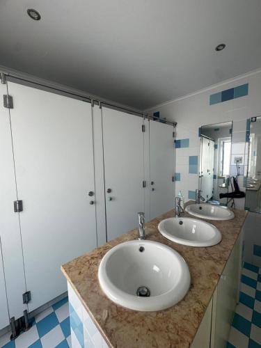 un bagno con tre lavandini e due specchi di 70's Hostel a Ericeira