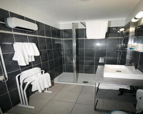 y baño con ducha y lavabo con toallas. en The Originals City, Hôtel Azur, Fos-sur-Mer, en Fos-sur-Mer