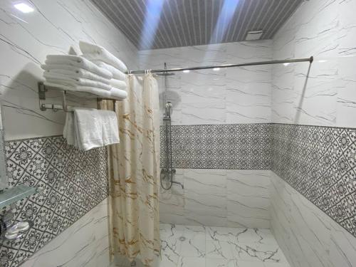 a bathroom with a shower with white towels at Hotel Imam Azam in Samarkand