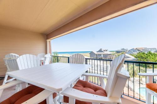 a table and chairs on the balcony with a view of the ocean at Good Trouble - Croatan Surf Club, Ocean View, Indoor and Outdoor Pool, Hot Tub, Pets Ok, YR Flex in Kill Devil Hills