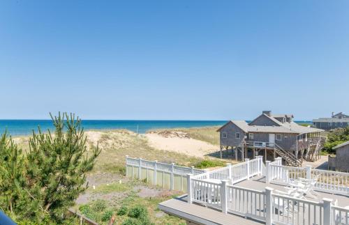 a house on the beach next to the ocean at Good Trouble - Croatan Surf Club, Ocean View, Indoor and Outdoor Pool, Hot Tub, Pets Ok, YR Flex in Kill Devil Hills