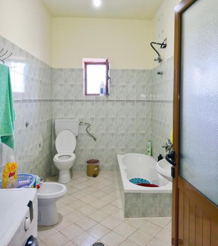 a bathroom with a toilet and a tub and a sink at Shtepi Manuel in Sarandë